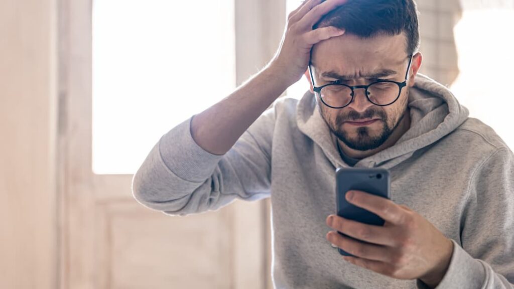 Um homem de óculos usa um espaço de cópia de smartphone. Golpe do PIX Errado